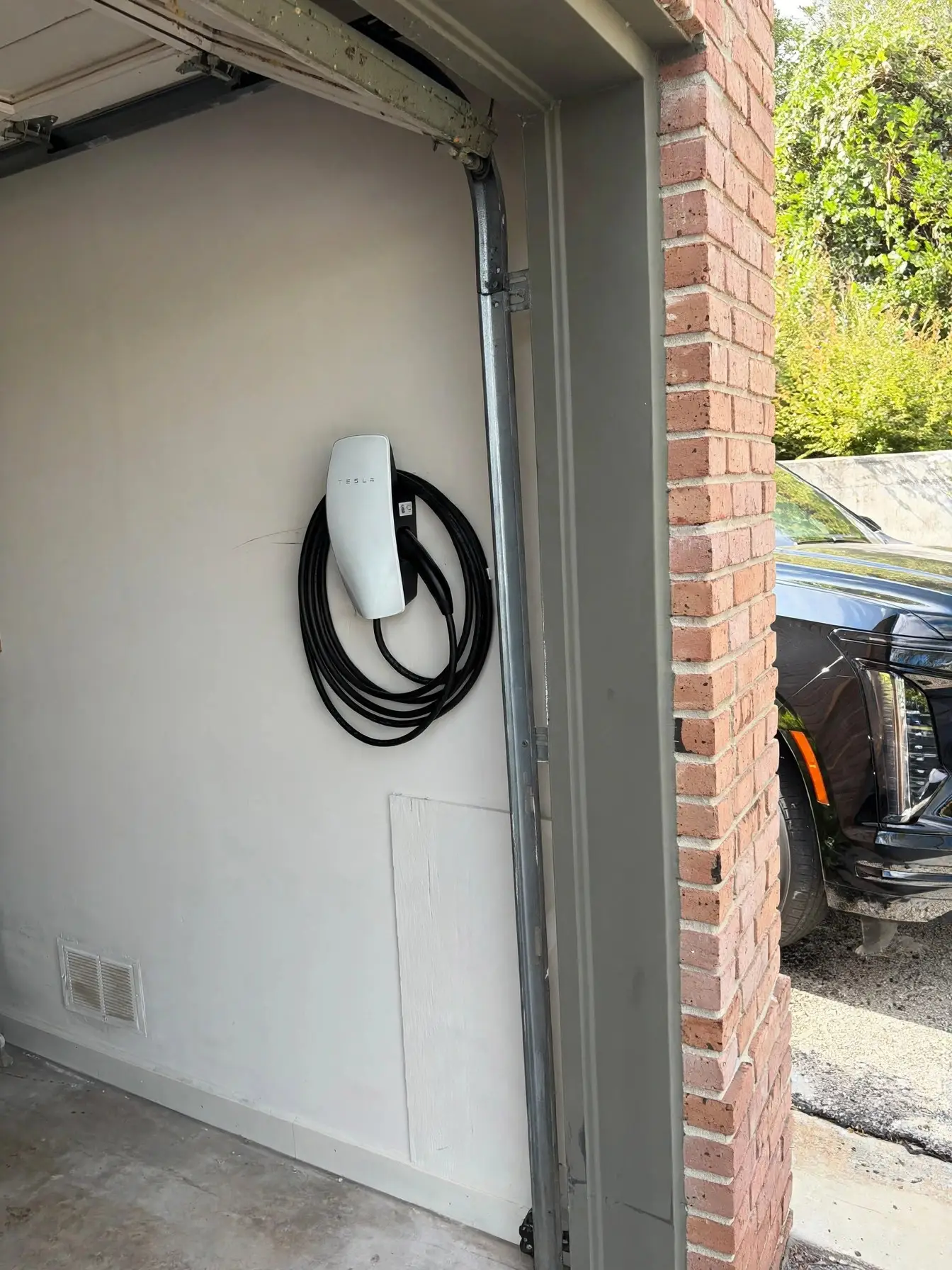 Tesla Wall Connector mounted inside a garage beside the door