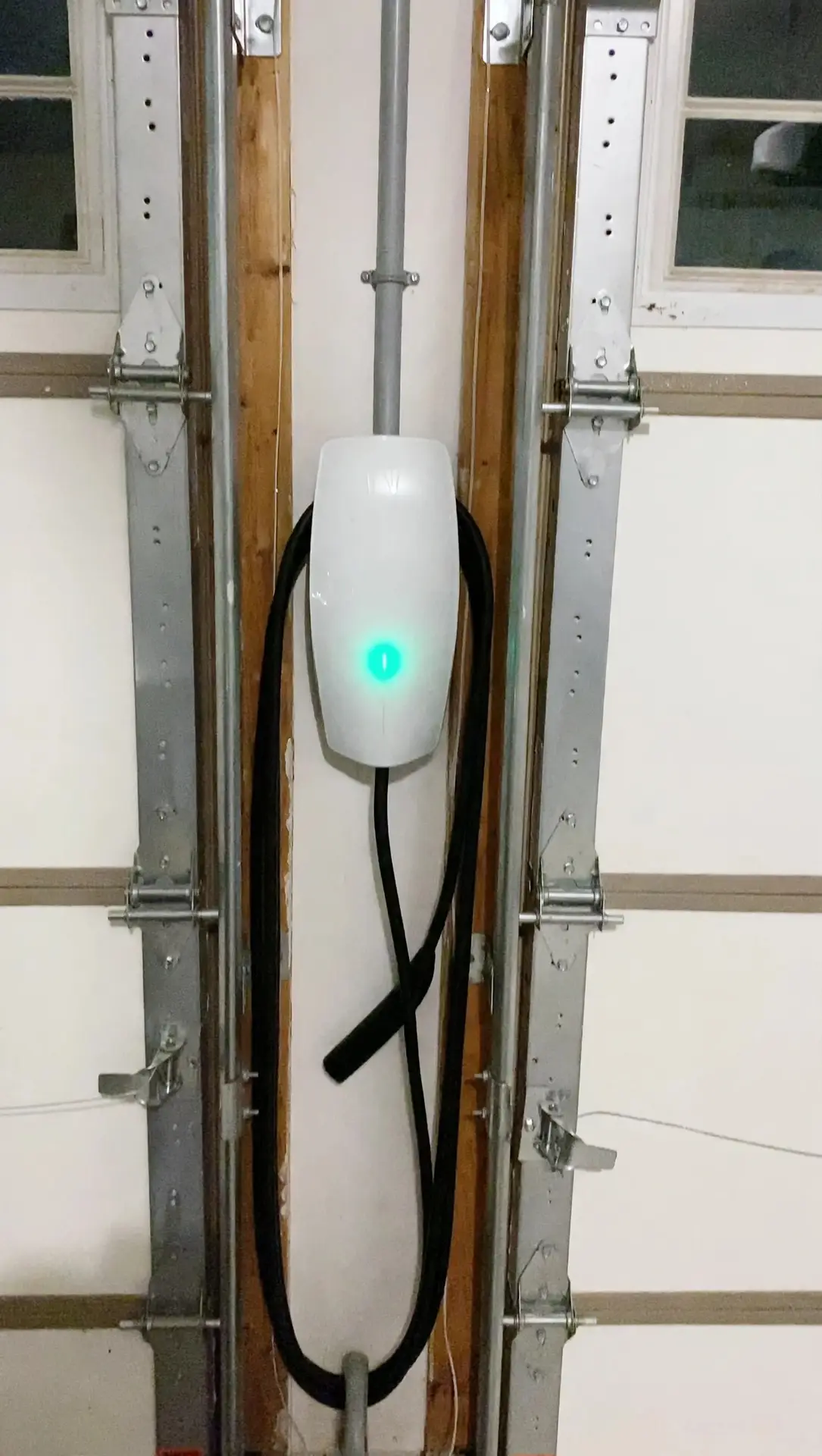 Wall Connector installed between garage door tracks, lit up while charging